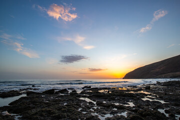 Sunset during a sans storm, Calima. Haze covered horizon turns orange as the sun sets as a sun ball. Volcanic beach landscape shot in Gran Tarajal, Canary Islands, Spain