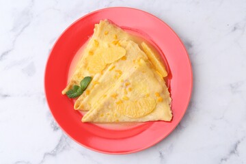 Plate with tasty crepes Suzette on white marble table, top view