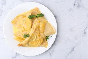 Plate with tasty crepes Suzette on white marble table, top view. Space for text