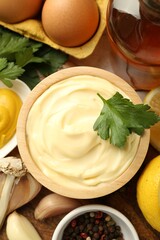 Delicious mayonnaise sauce with parsley, spices and products on table, flat lay