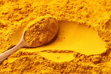 Turmeric powder in spoon on spice, closeup. Space for text