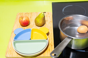 Preparation of healthy and nutritious varied baby food on induction stove by boiling egg in...