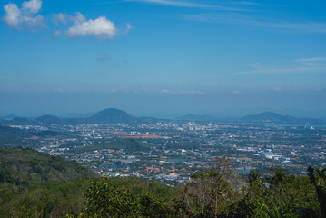 Elevated view of Phuket, Thailand, showing urban buildings, lush greenery, distant hills, and the...