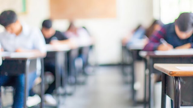 Classroom during Exam Period: Students taking an exam in a blurred classroom environment.
