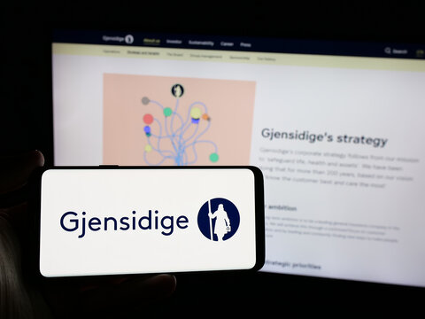 Stuttgart, Germany - 01-14-2025: Person holding smartphone with logo of Norwegian company Gjensidige Forsikring ASA on screen in front of website. Focus on phone display.