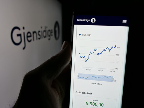 Stuttgart, Germany - 01-14-2025: Person holding cellphone with webpage of Norwegian company Gjensidige Forsikring ASA on screen in front of logo. Focus on center of phone display.