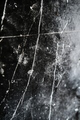 A close-up view of a black wall with graffiti marks and grime. A dark, textured background with visible scratches.