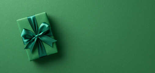 An elegant green gift box wrapped with satin ribbon, placed on a matching green background, perfect...