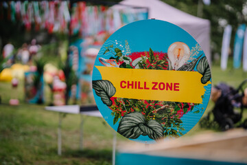 A colorful “Chill Zone” sign with tropical plants and a vibrant design, set in an outdoor event with a festive atmosphere and blurred background.