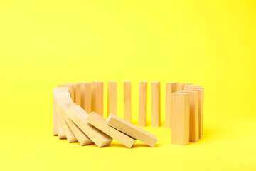 Domino effect. Wooden blocks falling on yellow background