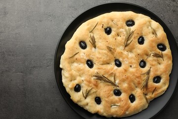 Delicious focaccia bread with olives and rosemary on grey table, top view. Space for text