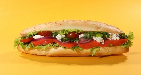Delicious baguette with salmon on yellow background, closeup