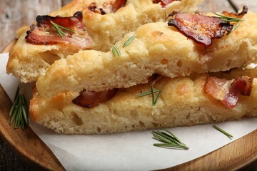 Slices of delicious focaccia bread with bacon and rosemary on table, closeup