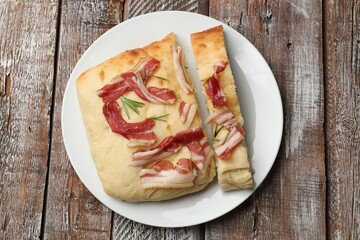 Pieces of delicious focaccia bread with bacon and rosemary on wooden table, top view