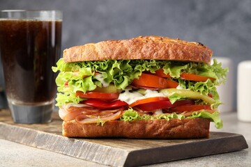 Delicious baguette sandwich with tomatoes and yellow beans on grey textured table, closeup