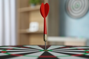 Red arrow hitting target on dart board indoors, closeup
