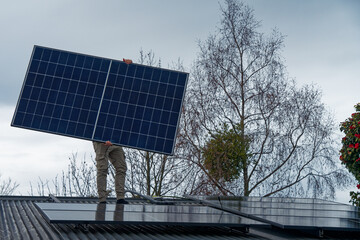 A person installing grid-tied photovoltaic solar panels on a traditional Kiwi villa with a...