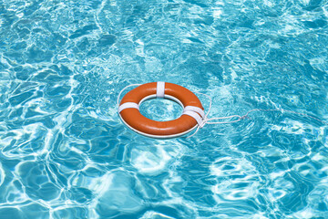 Safety equipment. Life buoy or rescue buoy floating on water. Ring for rescue. Help in water concept. Lifebelt on sea or pool. Orange inflatable ring floating in blue water. Life buoy for protect and