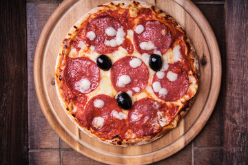Pizza with salami and mozzarella cheese. Wooden background. Soft focus. Top view. Close up.