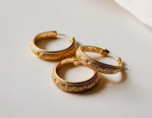 Elegant gold hoops with intricate detailing on a soft background.