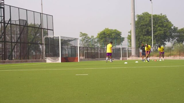 Group of male hockey players training for a game, working out on a field hockey pitch and doing strength exercises