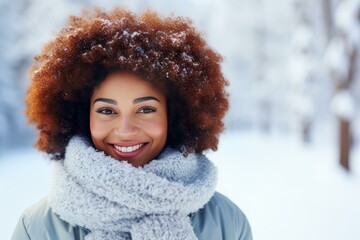 Young woman with curly hair and winter clothes smiling in a snowy forest