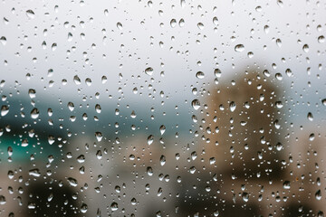 Raindrops on an apartment window. Close up, macro shot, blurred city building in the background, no people