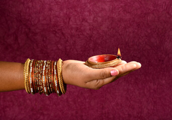 Female hand holding lit earthen lamp at Diwali festival in India