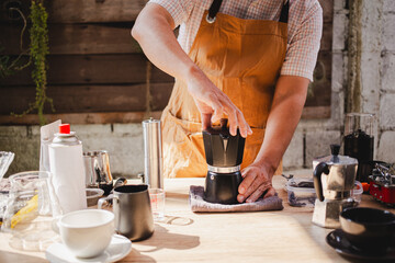 barista make classic Moka pot brews espresso over a portable on gas stove releasing fresh coffee aroma perfect outdoor brewing experience.