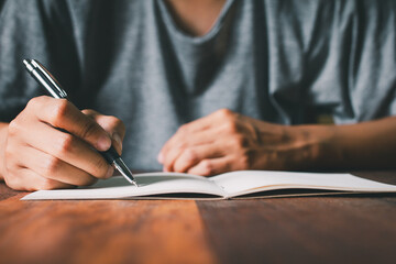 student writes in notebook, focusing on study homework, exam preparation. The moment learning and the pursuit of knowledge in an educational setting. Close up