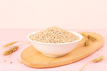 Bowl with spelt grain and ears on wooden table