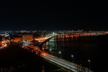 Fototapeta premium Cityscape at night with illuminated bridge and river reflections.