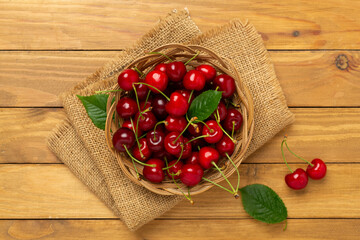 Fresh cherries in bowl on wooden background, top view