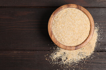 Oat bran in bowl on wooden table, top view. Space for text