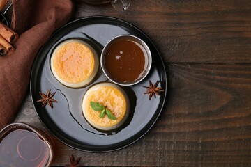 Tasty puddings with caramel sauce served on wooden table, flat lay. Space for text