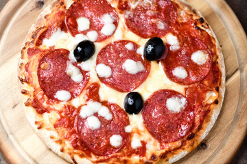 Pizza with salami and mozzarella cheese. Wooden background. Soft focus. Top view. Close up