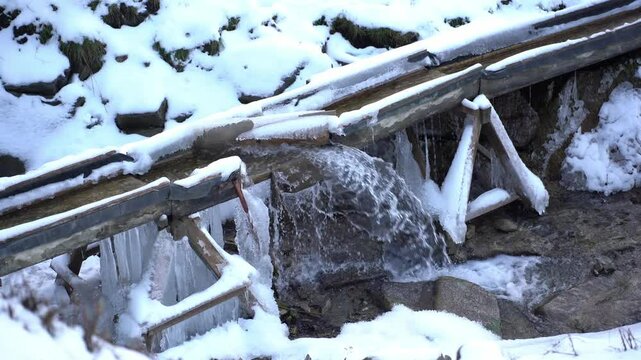 mountain water is diverted from a Romanian farm aqueduct into a stream below during excess winter water generated by snowfall