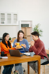 Teamwork and creativity with young adults collaborating on laptops and tablets in a cozy workspace.