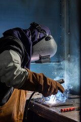 Fototapeta premium A skilled welder is intensely focused on welding metal pieces, showcasing the sparks and bright light characteristic of the welding process in an industrial environment.
