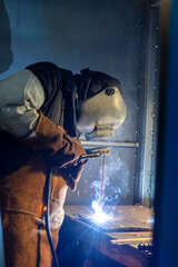 Fototapeta premium A skilled welder is intensely focused on welding metal pieces, showcasing the sparks and bright light characteristic of the welding process in an industrial environment.