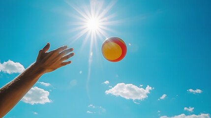 Bright blue sky with fluffy white clouds as a beach ball is being tossed playfully up in the air capturing the vibrant summer vacation and leisure activity
