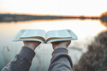Bible in the hands of a girl, concept morning prayer in nature