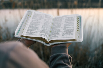 Bible in the hands of a girl, concept morning prayer in nature