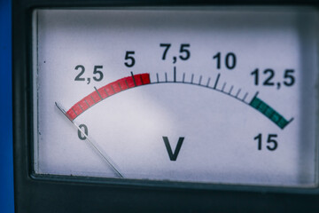 Close-up of a voltage meter displaying readings on a white dial with a red and green scale....