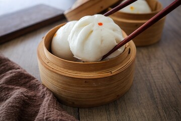 steamed stuff bun,steamed dumpling,stuffed steamed bun,thai called sarapao in white plate on wooden background