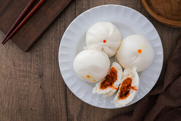 steamed stuff bun,steamed dumpling,stuffed steamed bun,thai called sarapao in white plate on wooden background
