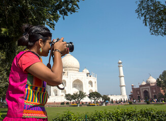 Young woman tourist taking photos of Taj Mahal,
