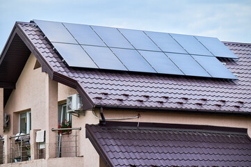 Fototapeta premium House with solar panels on rooftop for generating electricity through photovoltaic effect. Home with solar power system on roof. Concept of alternative energy, autonomy, power sustainable resources.