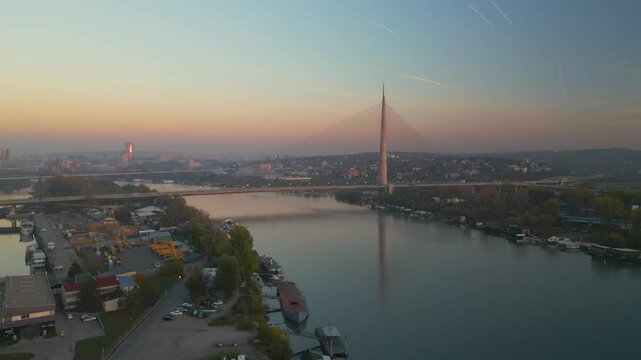 Aerial 4K push-in shot of the historic Ada Bridge pylon over the Sava river at sunset, Belgrade, Serbia