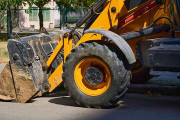 A bulldozer with a large bucket stands on an asphalt road